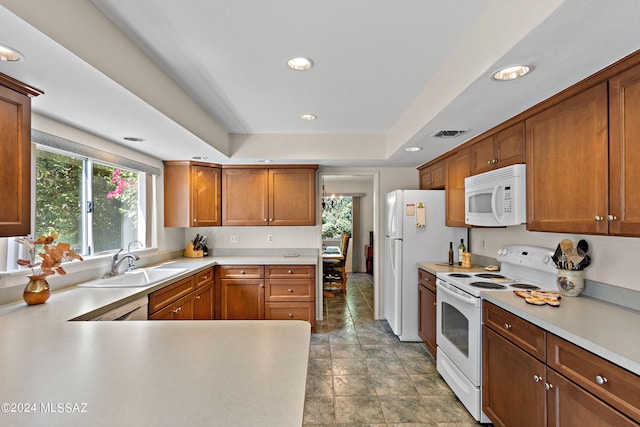 kitchen with white appliances, a tray ceiling, and sink