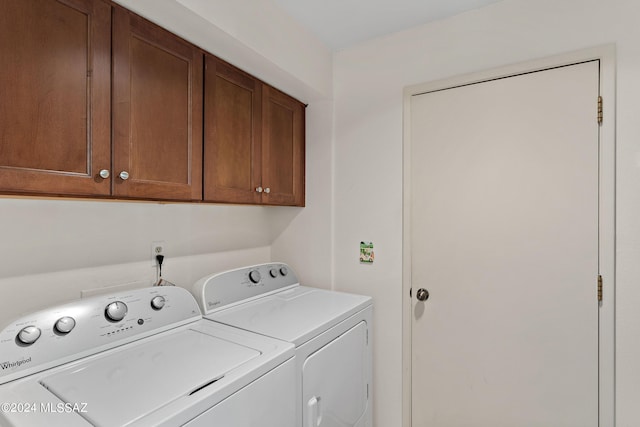 clothes washing area featuring cabinets and washer and clothes dryer