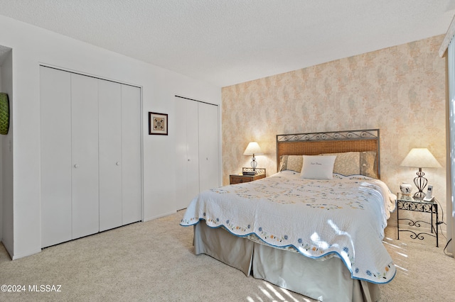 bedroom featuring multiple closets, carpet floors, and a textured ceiling