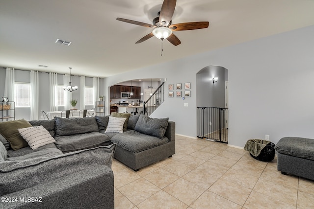 living room with light tile patterned flooring and ceiling fan with notable chandelier