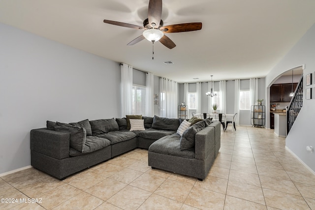 living room featuring light tile patterned floors, ceiling fan with notable chandelier, and a wealth of natural light