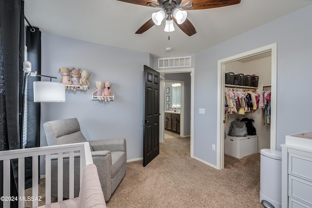 bedroom featuring a closet, light colored carpet, a crib, and ceiling fan