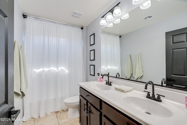 bathroom with toilet, vanity, and tile patterned flooring