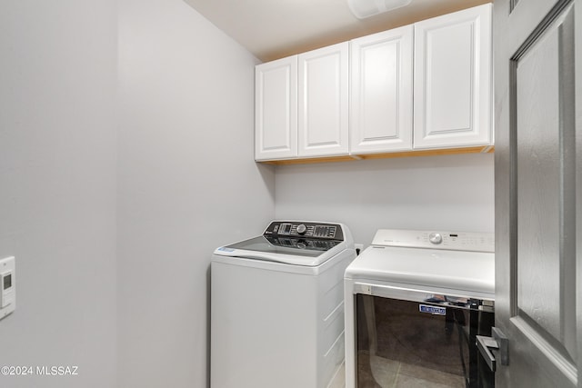 clothes washing area with washer and clothes dryer and cabinets