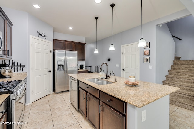 kitchen featuring dark brown cabinets, stainless steel appliances, a center island with sink, sink, and light stone counters