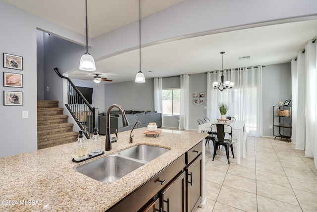 kitchen featuring sink, ceiling fan with notable chandelier, pendant lighting, light stone counters, and light tile patterned floors