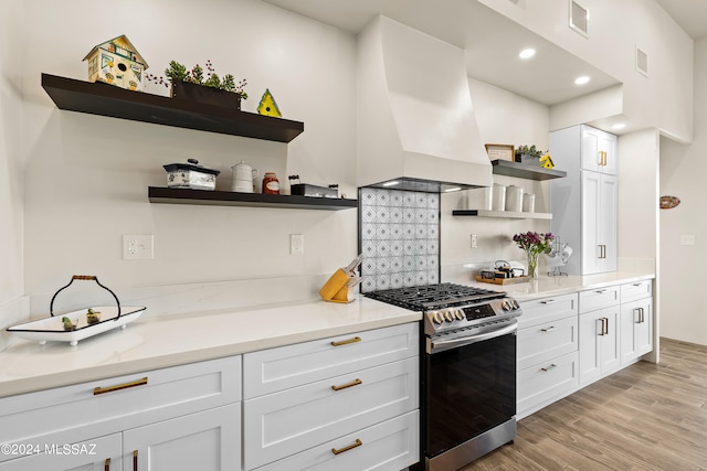 kitchen featuring light hardwood / wood-style flooring, white cabinetry, custom range hood, light stone countertops, and stainless steel range with gas cooktop