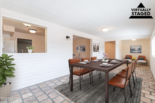 dining space featuring brick wall