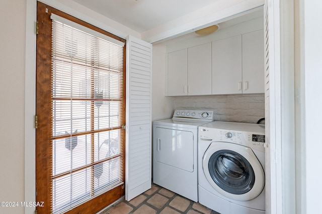 clothes washing area with washing machine and dryer and cabinets