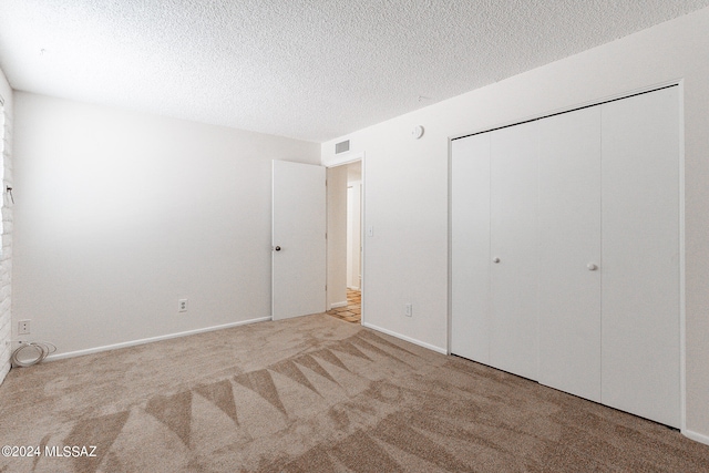 unfurnished bedroom with a textured ceiling, light colored carpet, and a closet