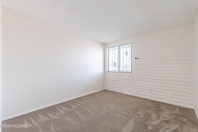 empty room featuring brick wall, a textured ceiling, and carpet