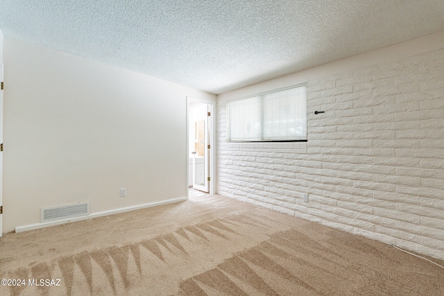 empty room featuring light carpet, a textured ceiling, and brick wall