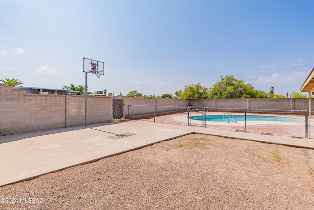 view of sport court with a fenced in pool