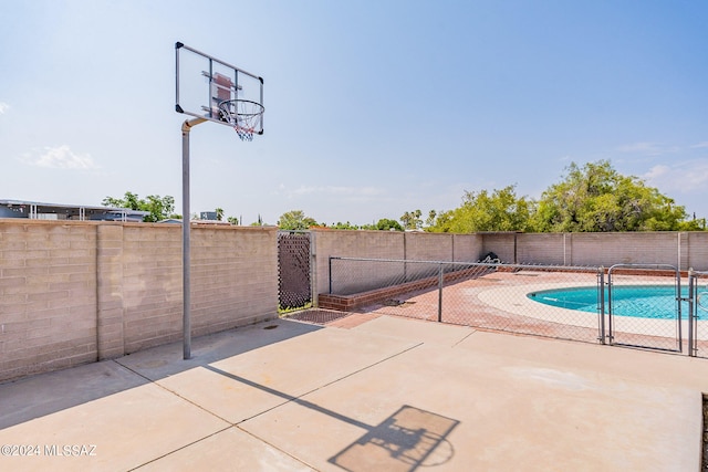 view of basketball court with a fenced in pool