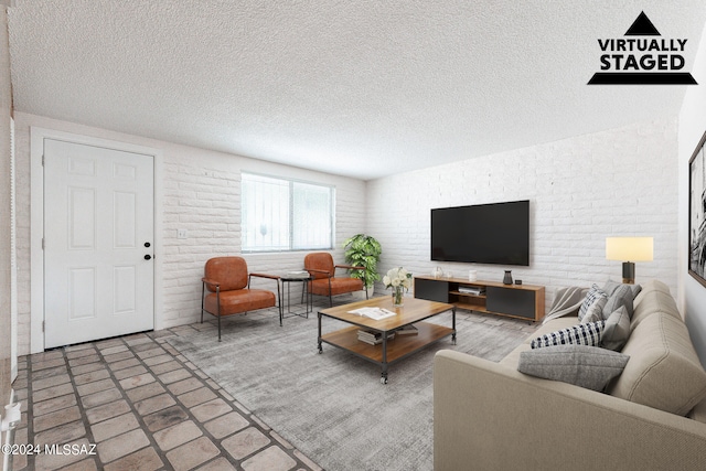 living room with brick wall and a textured ceiling