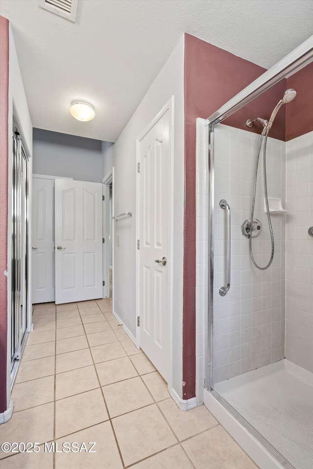 bathroom featuring a shower with shower door and tile patterned floors