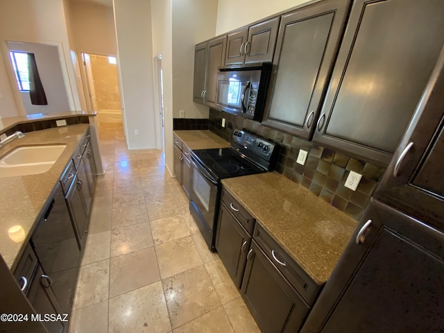 kitchen featuring backsplash, dark stone countertops, black appliances, and sink