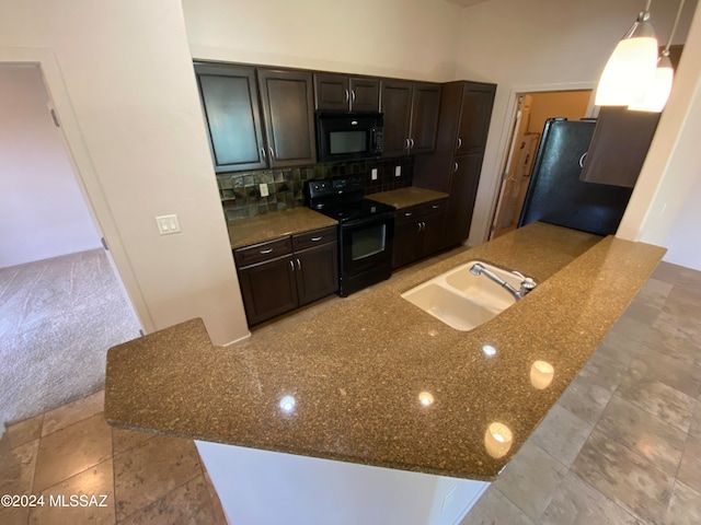 kitchen with dark stone countertops, sink, kitchen peninsula, and black appliances