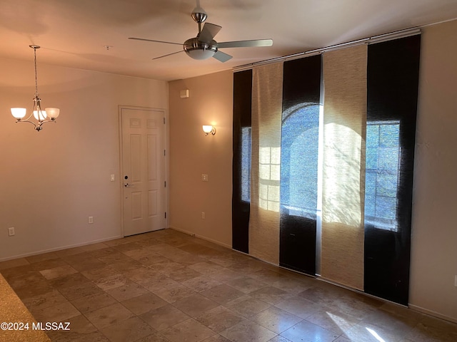 unfurnished room with ceiling fan with notable chandelier