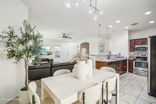 dining space with sink, light tile patterned floors, and ceiling fan