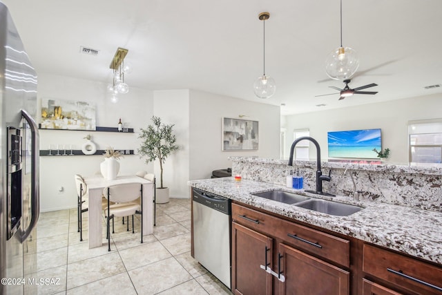 kitchen with stainless steel appliances, a wealth of natural light, light stone countertops, and sink