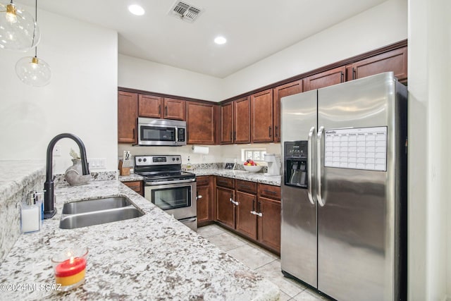 kitchen with light stone counters, stainless steel appliances, light tile patterned floors, hanging light fixtures, and sink