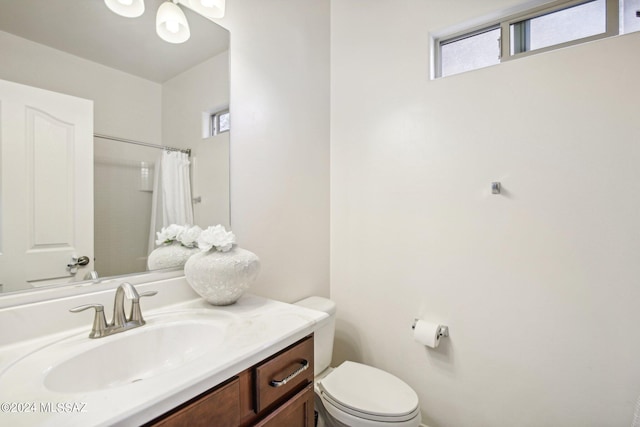 bathroom featuring curtained shower, vanity, and toilet