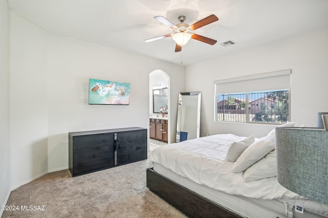 bedroom with ensuite bathroom, carpet flooring, and ceiling fan