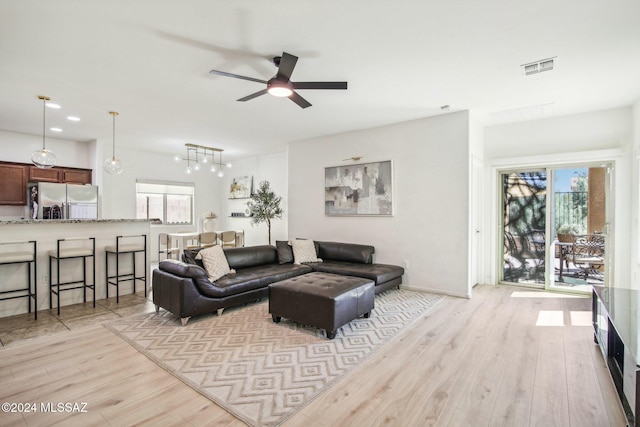 living room featuring light wood-type flooring, ceiling fan, and plenty of natural light