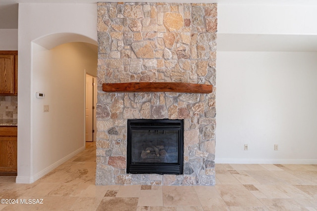 interior details featuring arched walkways, a stone fireplace, and baseboards