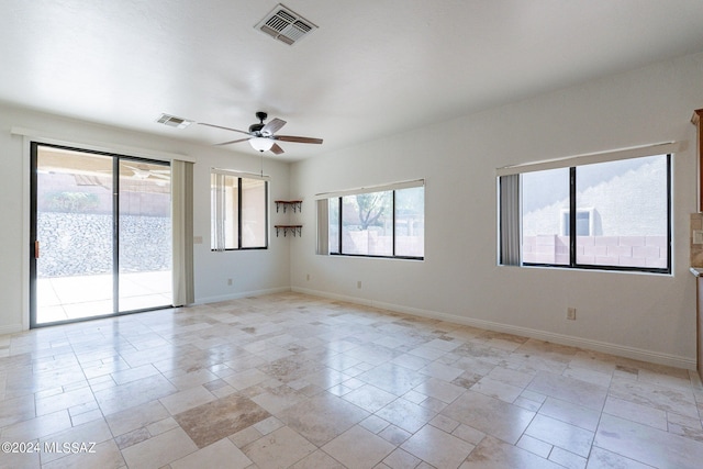 spare room with baseboards, a ceiling fan, and visible vents