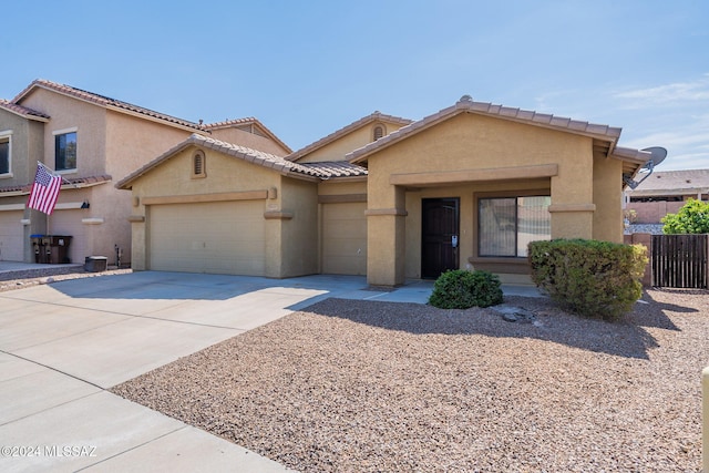 view of front of property featuring a garage, a tile roof, concrete driveway, and stucco siding