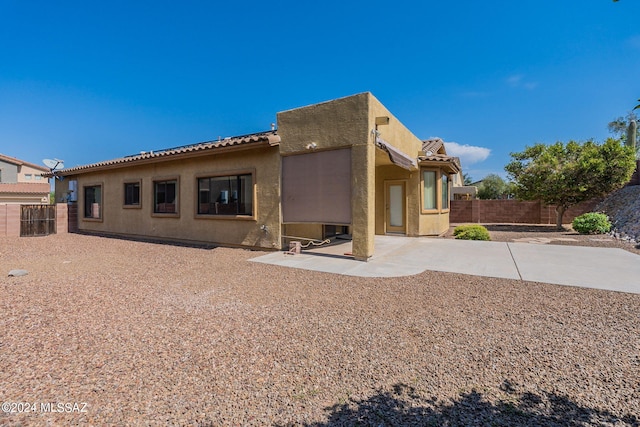 rear view of property with a fenced backyard, a patio area, and stucco siding