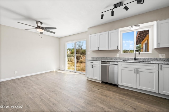 kitchen with light stone counters, white cabinets, sink, dishwasher, and hardwood / wood-style flooring