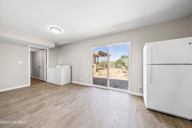 interior space featuring washer and clothes dryer, light wood-type flooring, and white fridge