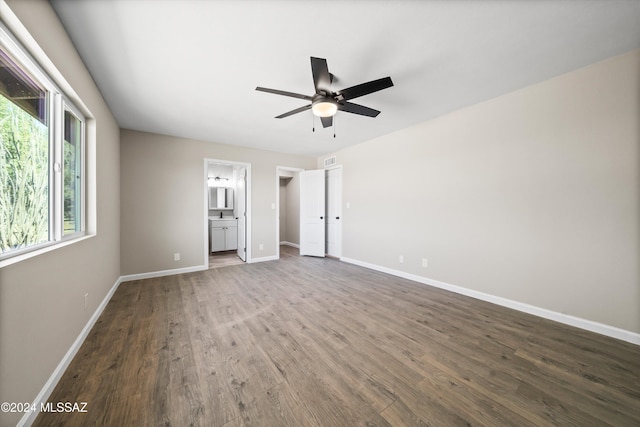 unfurnished bedroom with ensuite bath, ceiling fan, and dark wood-type flooring