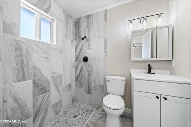 bathroom with a tile shower, vanity, and toilet