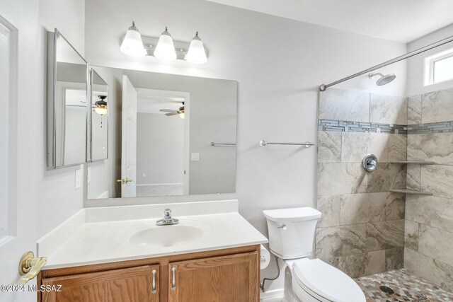 bathroom featuring a tile shower, vanity, toilet, and ceiling fan