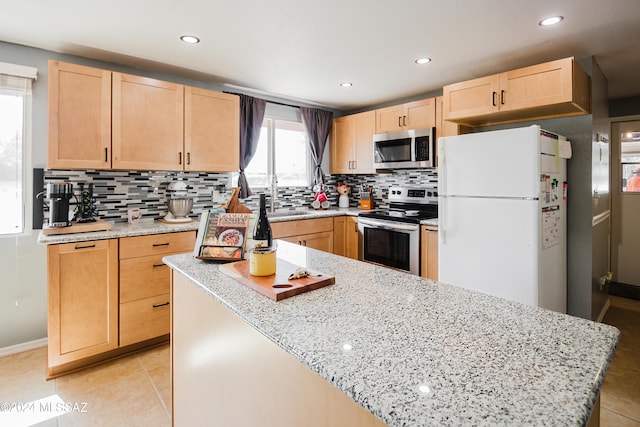 kitchen with light brown cabinetry, sink, stainless steel appliances, and tasteful backsplash