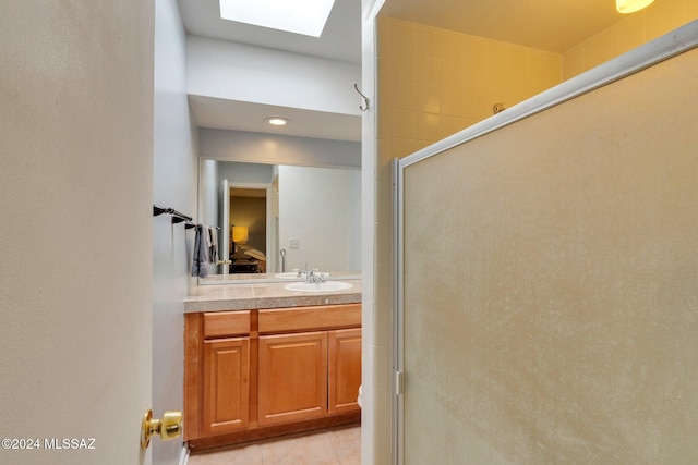 bathroom with walk in shower, a skylight, vanity, and tile patterned floors