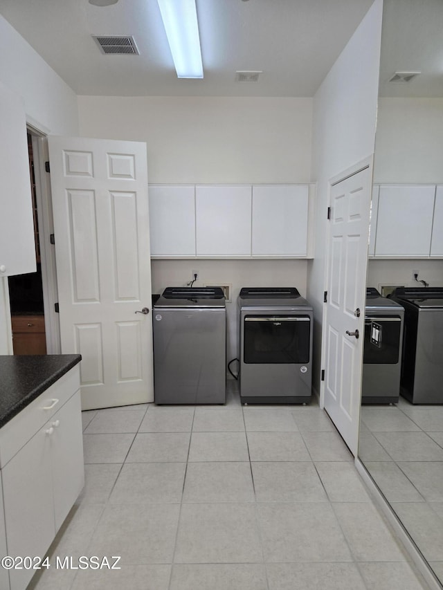 washroom with cabinets, independent washer and dryer, and light tile patterned flooring