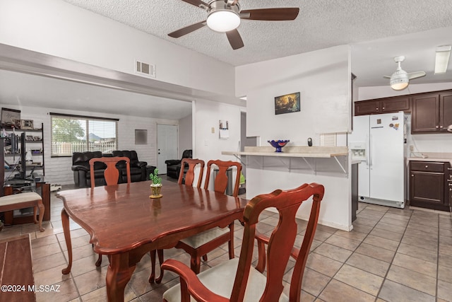 dining space featuring ceiling fan, light tile patterned floors, and a textured ceiling