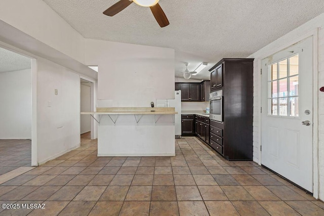 kitchen featuring light countertops, a ceiling fan, a textured ceiling, and oven