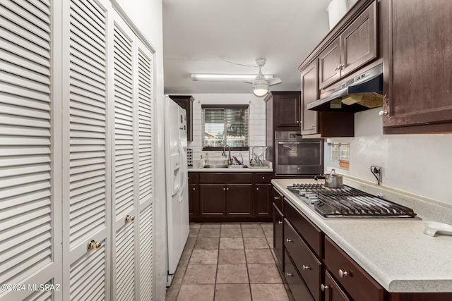 kitchen featuring dark brown cabinets, light tile patterned floors, appliances with stainless steel finishes, and sink