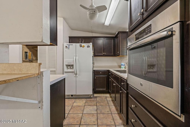kitchen with lofted ceiling, white fridge with ice dispenser, dark brown cabinetry, a ceiling fan, and stainless steel oven