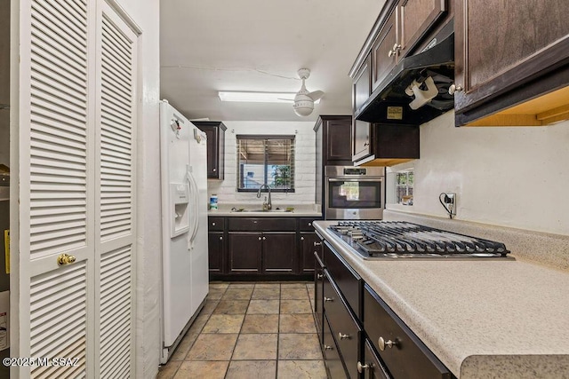 kitchen featuring dark brown cabinetry, a sink, appliances with stainless steel finishes, and under cabinet range hood