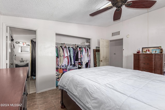 tiled bedroom featuring a textured ceiling, vaulted ceiling, ceiling fan, and a closet