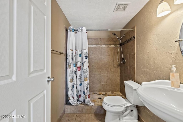 full bath with a sink, a shower stall, tile patterned floors, toilet, and visible vents