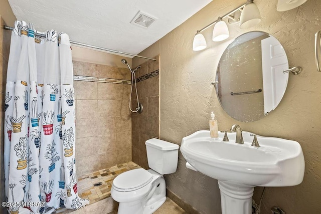 full bathroom featuring a shower stall, toilet, a textured wall, a sink, and visible vents