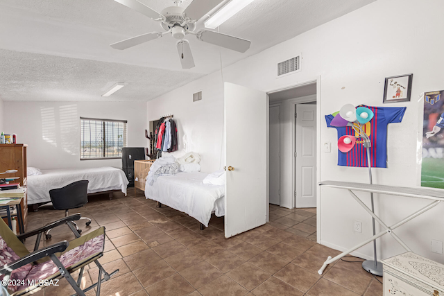 tiled bedroom with a textured ceiling and ceiling fan